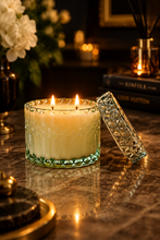 Load image into Gallery viewer, A clear textured glass candle jar filled with creamy white wax, shown on a wooden tabletop with its matching patterned glass lid leaning against it. The background is softly blurred.