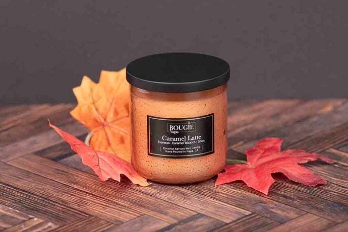 Jar of 'Bougie' Caramel Latte candle with autumn leaves on a wooden surface