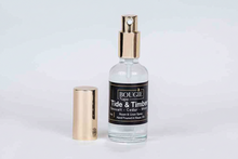Load image into Gallery viewer, A clear glass room and linen spray bottle with a gold spray nozzle and a black label reading 'BOUGIE Napa Tide &amp; Timber', shown next to its detached gold cap on a light background.
